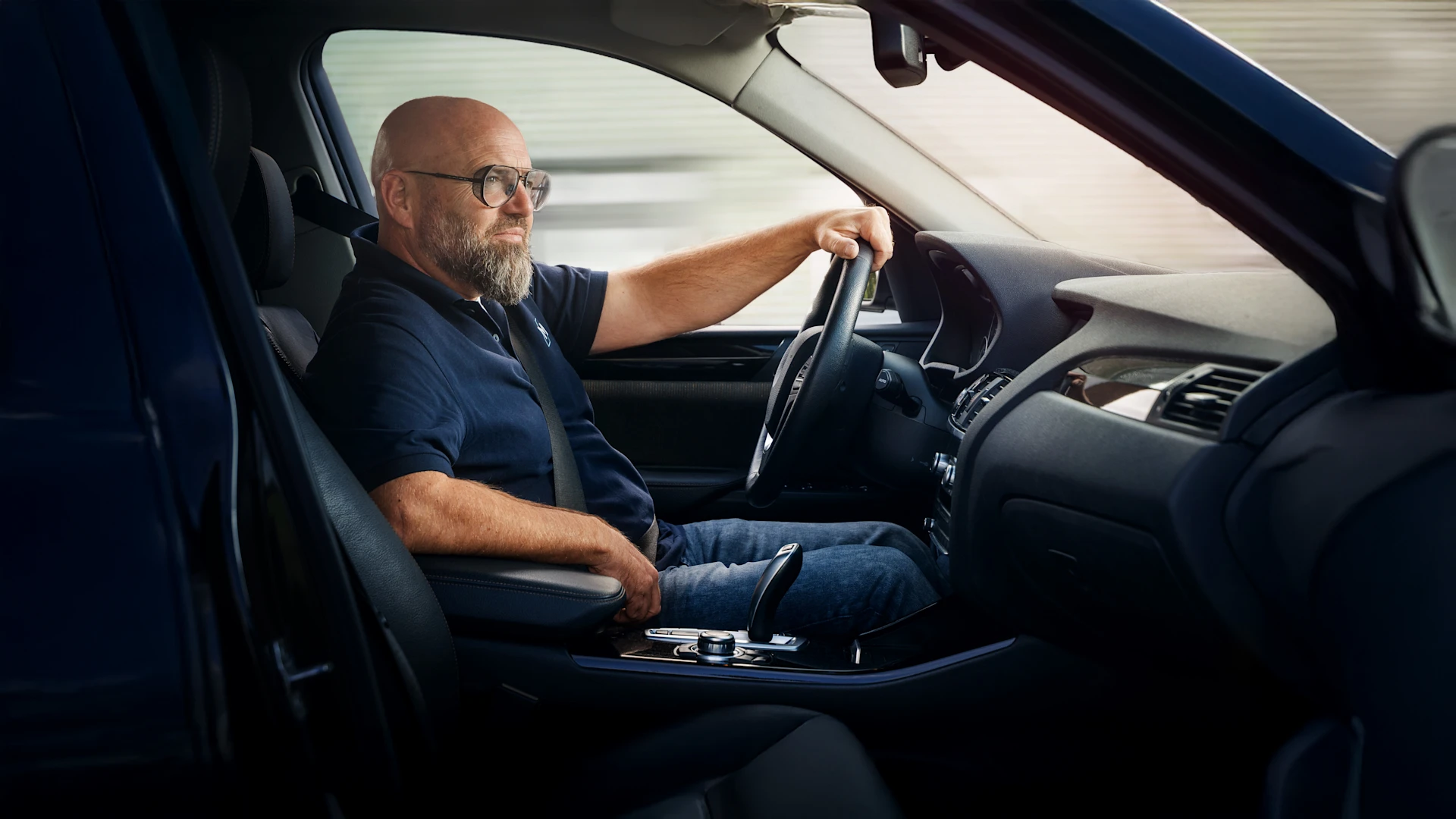 Mann sitzt am Steuer eines Autos mit Automatikgetriebe und hält während der Fahrt das Lenkrad.